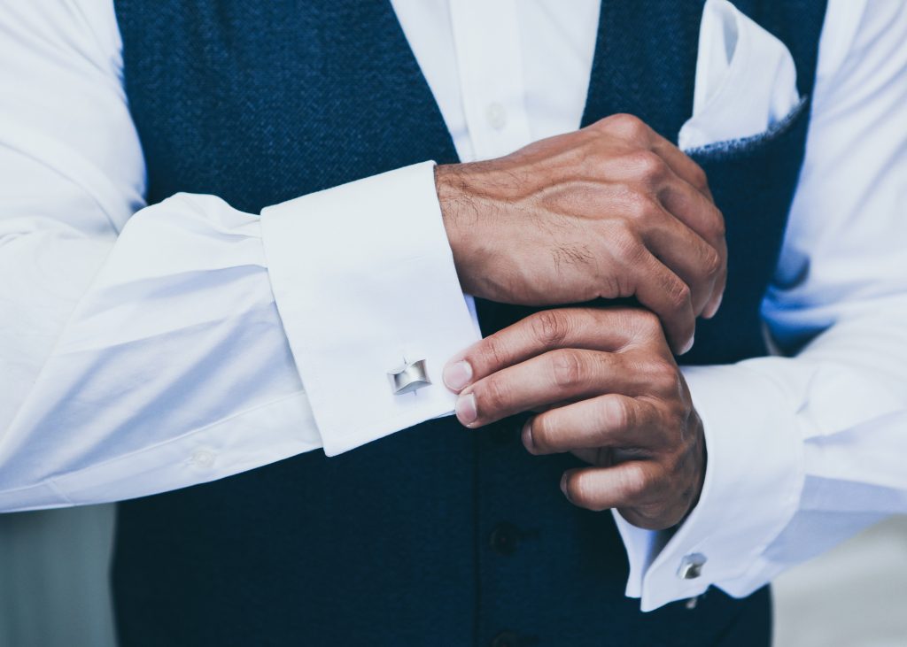 How to Pick the right cufflinks - Man adjusting silver cufflinks on white dress shirt